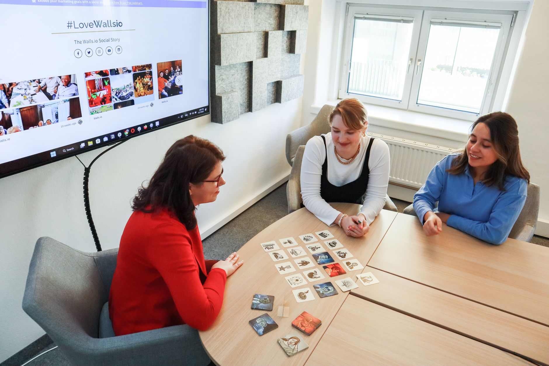 Team of game developers discussing designs around a large monitor in a modern office.